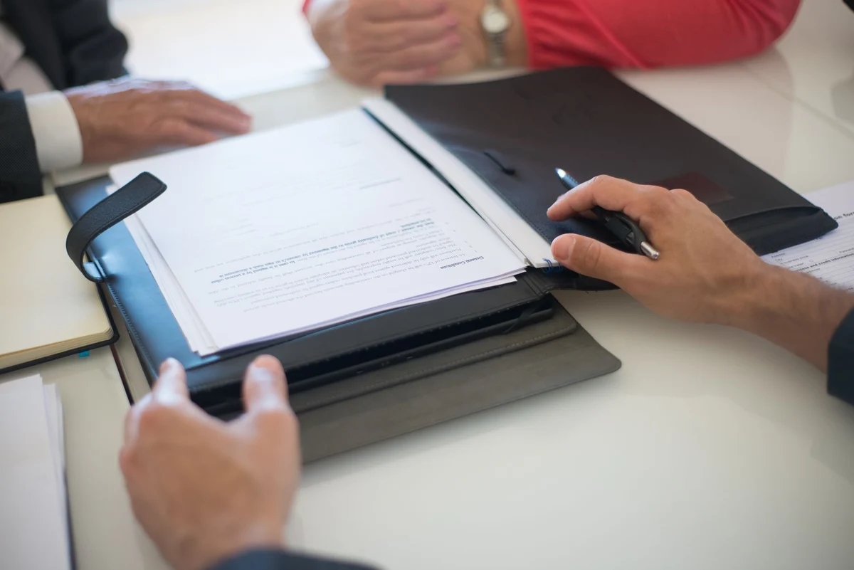 People discussing documents during a consultation at a table.
