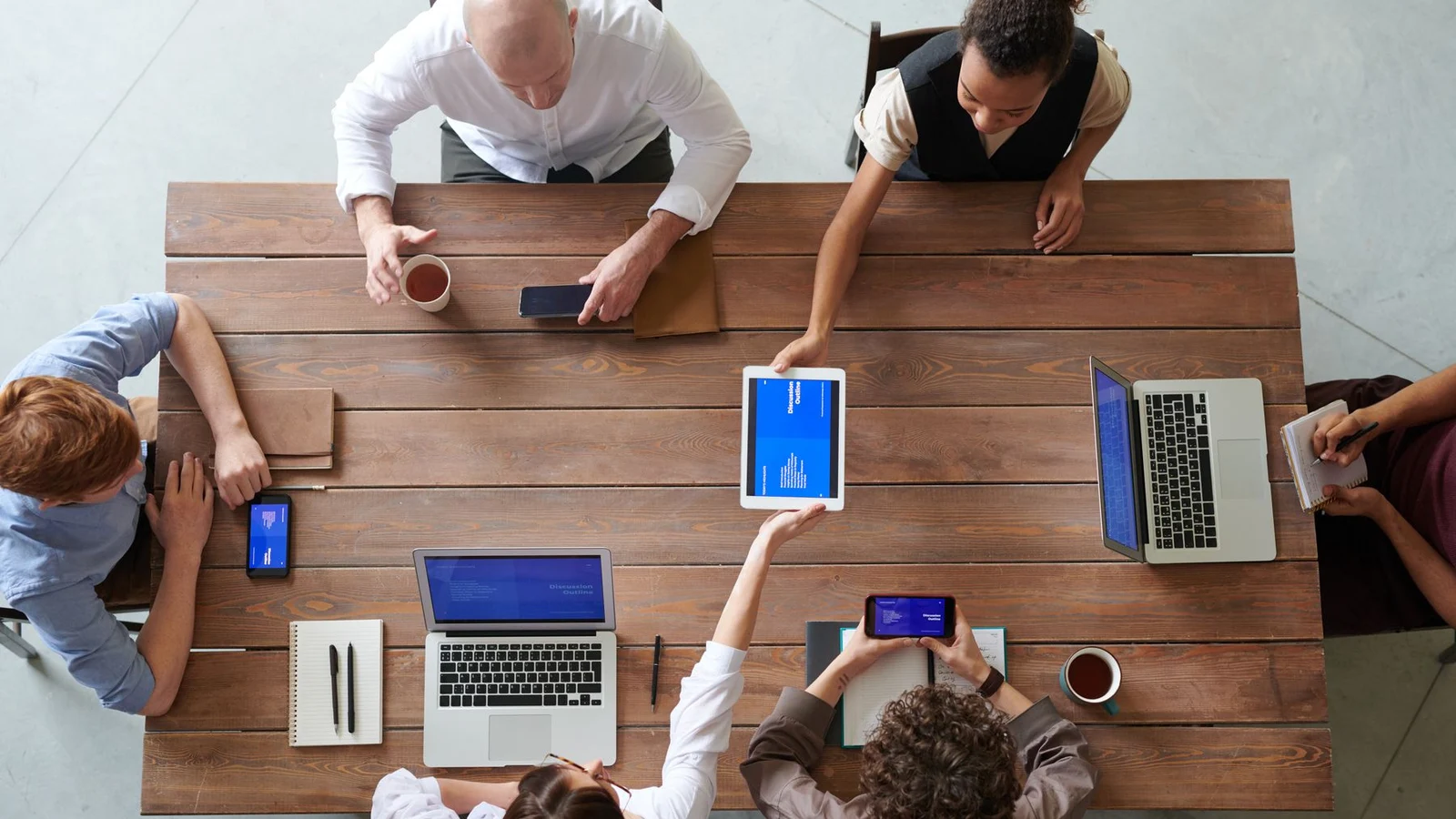 Unmasked business professionals reviewing information and planning work together around a meeting table.